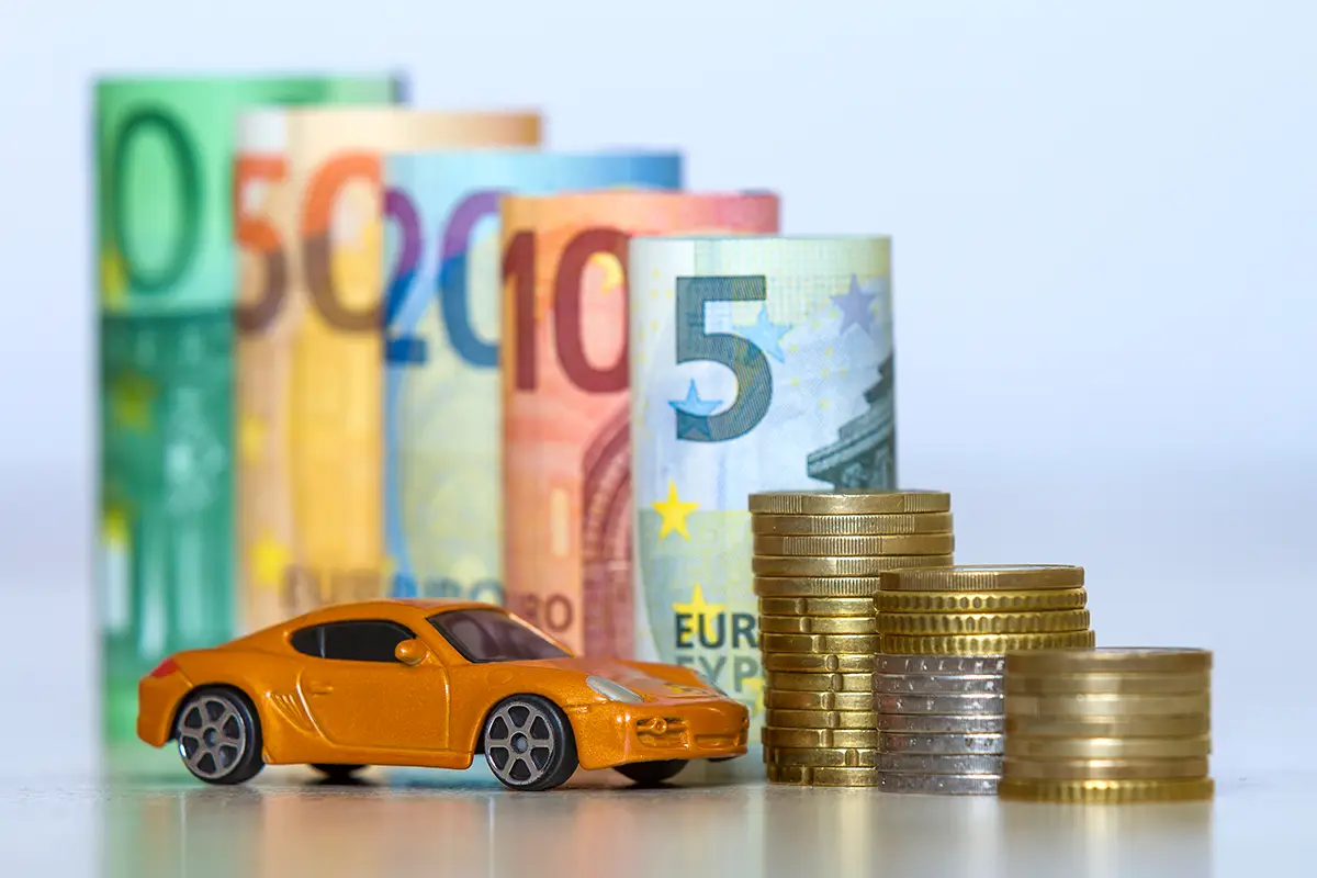 Aufgerollte Geldscheine und Münzen mit einem Spielzeug auto